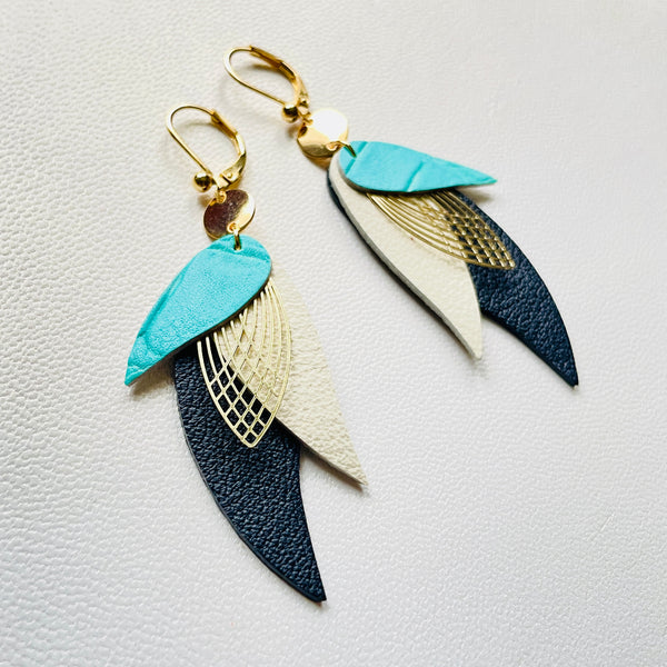 boucles d'oreilles dorées Nune modèle Ara en plumes de cuirs turquoise lézard, blanc cassé mat et noir grainé sur cuir blanc