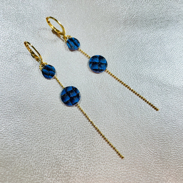 Fines boucles d'oreilles Lyre de Nune, dorées à l'or fin avec petites pastilles de cuir marin, cuir de poisson saumon bleus saphir écaille sur chaînette dorée, sur fond gris argenté