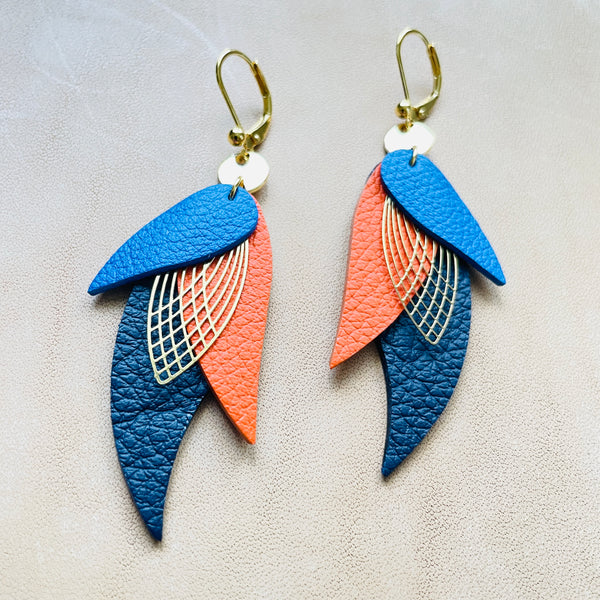 boucles d'oreilles dorées Nune modèle Ara en plumes de  cuirs bleu roi grainé, carotte grainé et bleu mariné grainé sur cuir beige