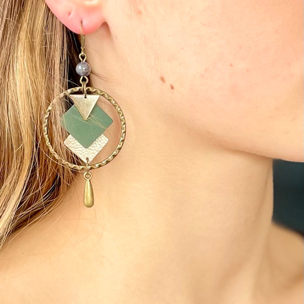 Boucles d'oreille en bronze Nune modèle Adamante Créoles en cuir vert sapin portée par un modèle aux cheveux blonds et au teint pâle