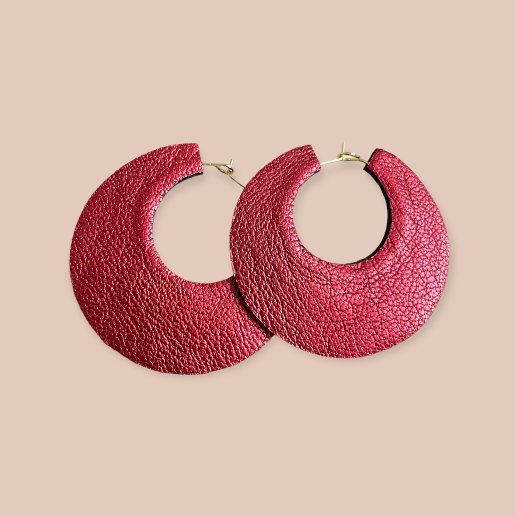 NUNE grandes boucles d'oreilles créoles dorées rondes tout-cuir Circus, vues à plat, côté rubis métallisé