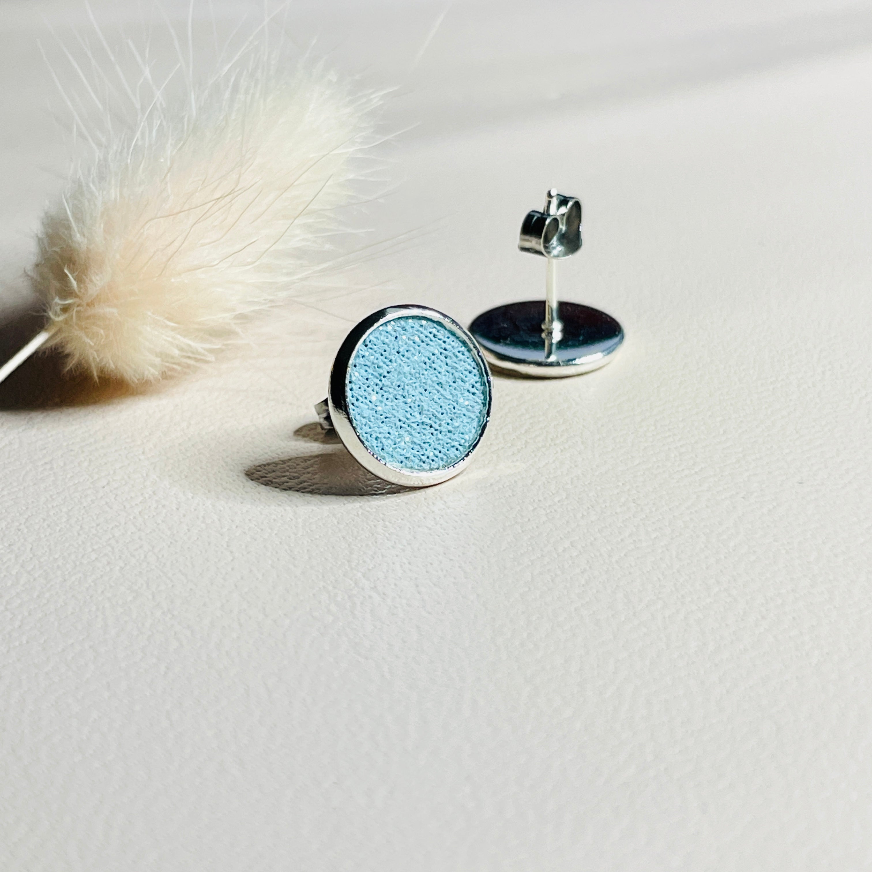 Puces d'oreilles argentées rondes Nune modèle Ilis argenté avec pastilles de cuir topaze pailleté, sur fond de cuir blanc cassé