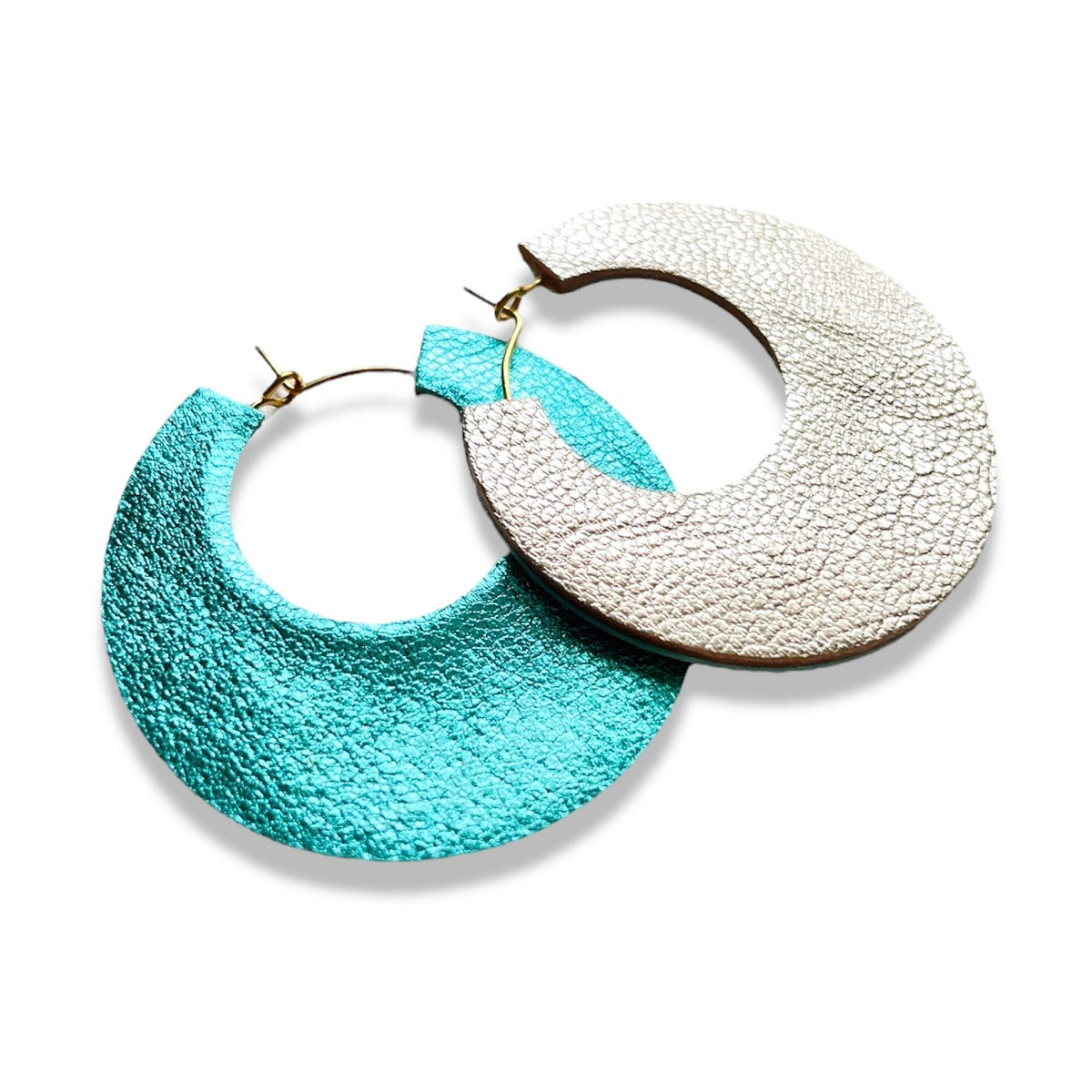 NUNE grandes boucles d'oreilles créoles dorées rondes tout-cuir Circus, un côté cuir argent, l'autre côté cuir turquoise métallisé à plat sur fond blanc