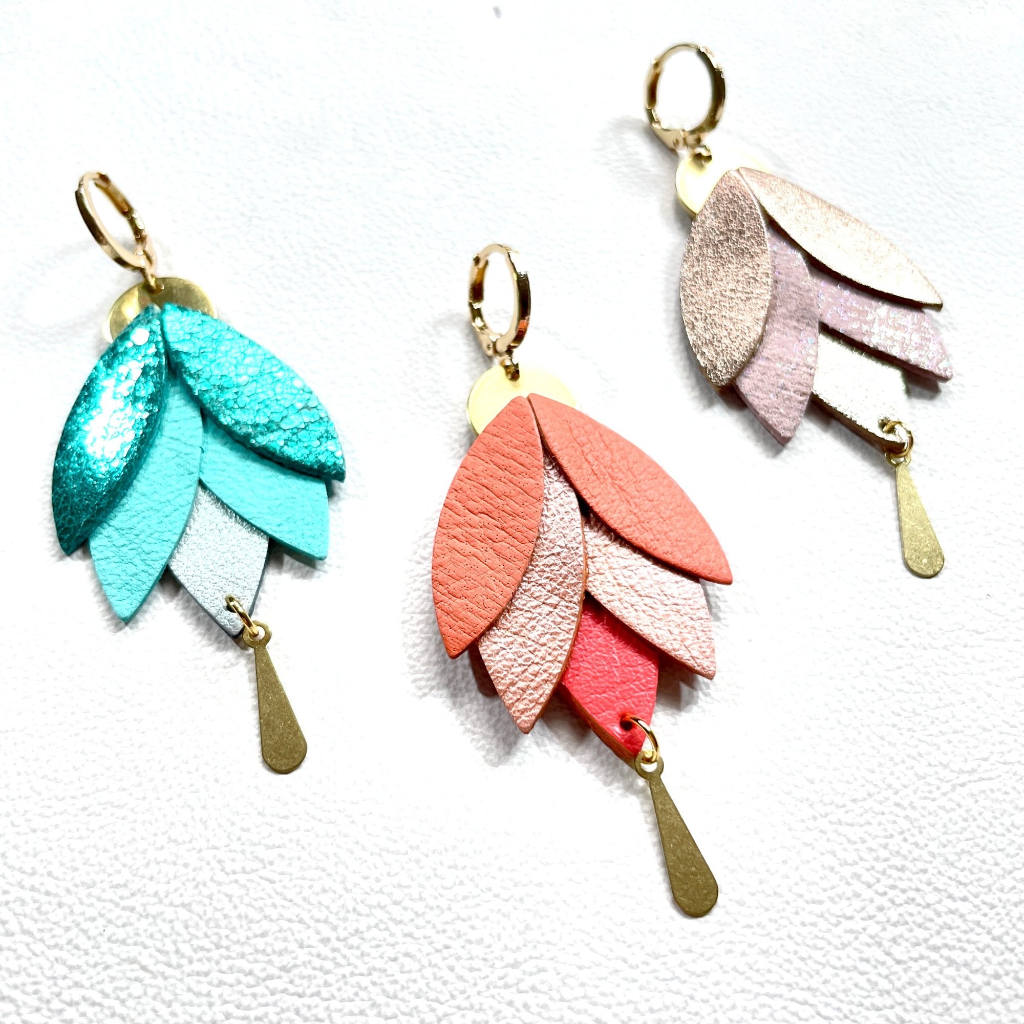 Boucles d'oreilles dorées pendantes  Nune modèle Nymphéa en cuirs recyclés dans les tons verts, corail, rosé irisé, sur fond blanc