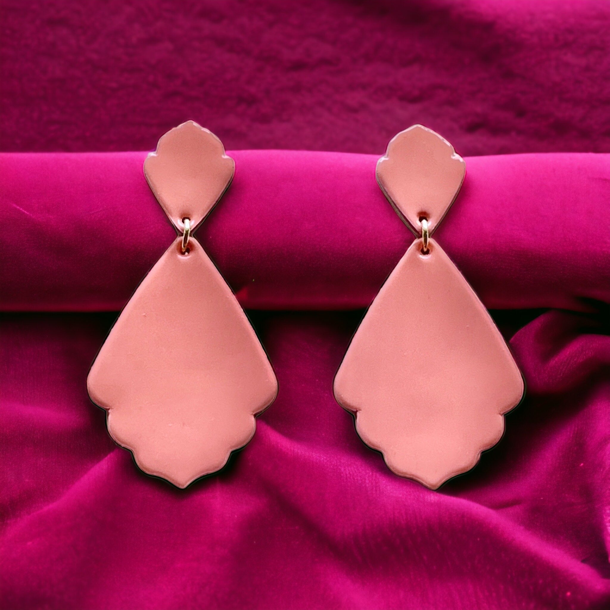 paire de boucles d'oreilles vieux rose vernis de style rétro baroque, sur fond velours fushia