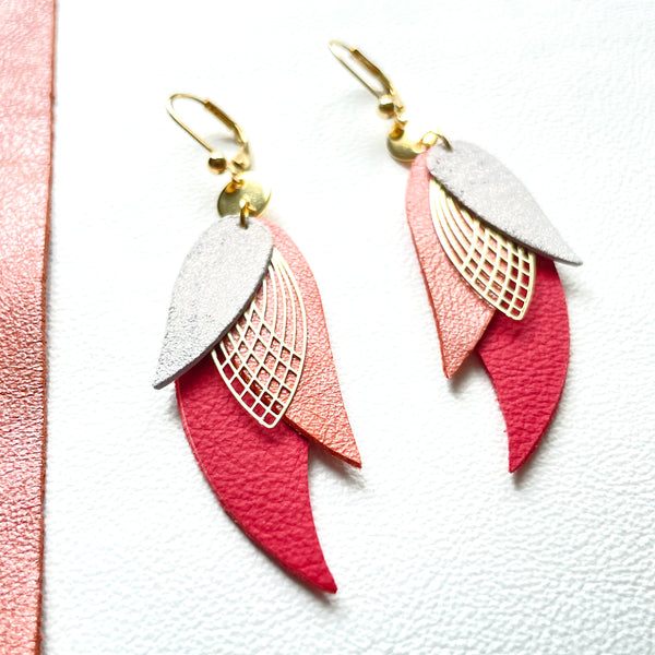 boucles d'oreilles dorées Nune modèle Ara en plumes de cuir gris pailleté, corail nacré et rouge foncé mat sur fond blanc