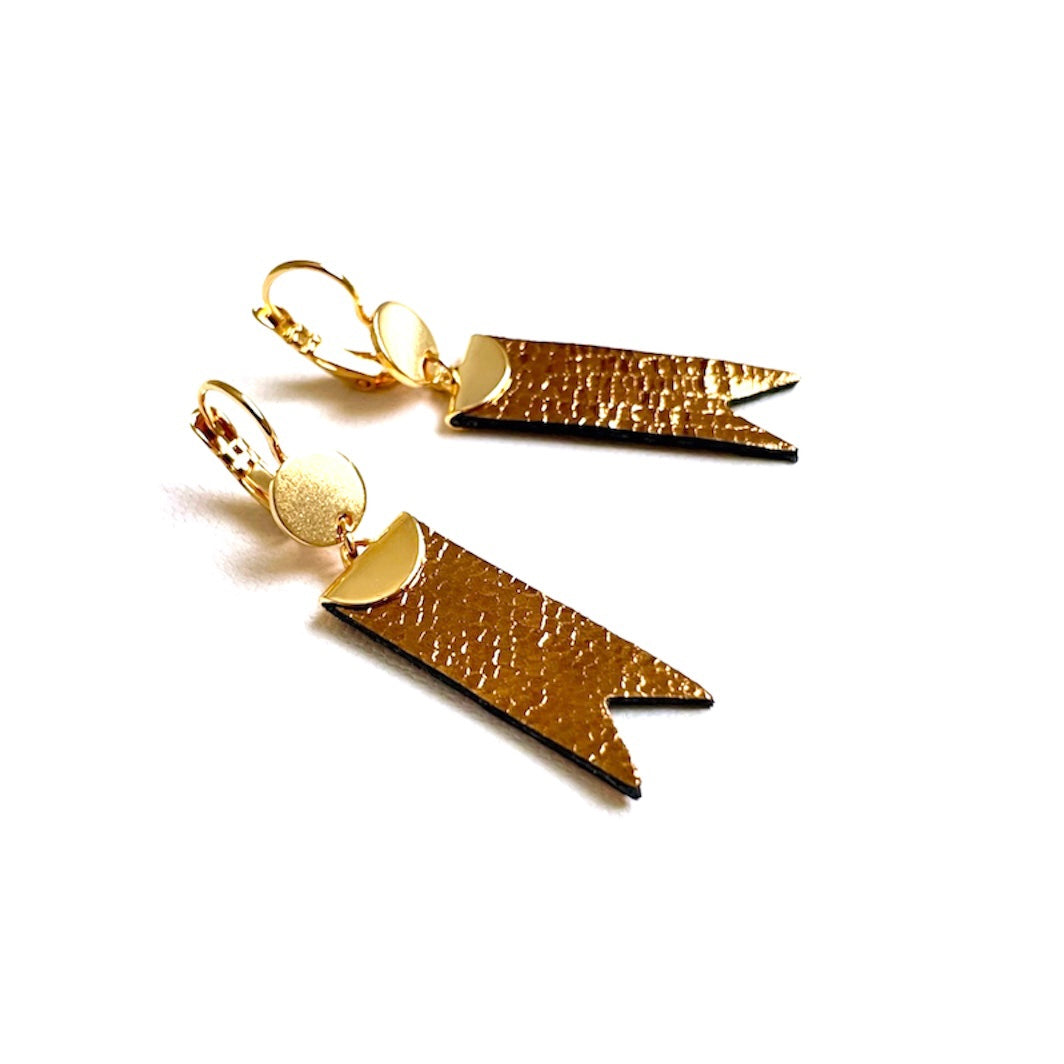 Boucles d'oreilles dorées Nune modèle Cinta en forme de rubans en cuir bronze brillant façon serpent, sur fond blanc