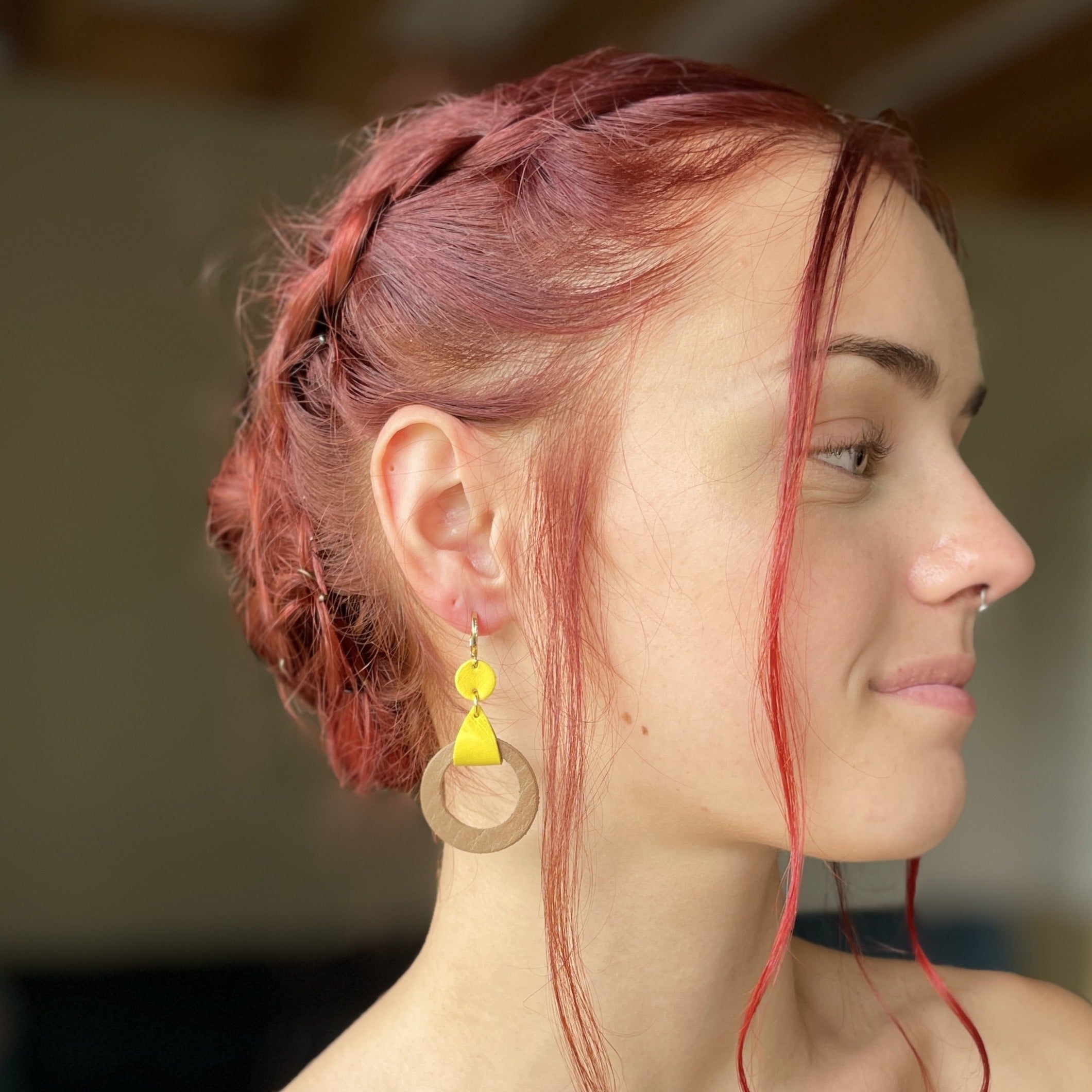 boucle d'oreille dorée Nune modèle Cyllène en cuirs beige amande et jaune citron portée par un modèle de profil aux cheveux rouges et au teint pâle