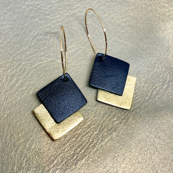 NUNE boucles d'oreilles créoles Adalis dorées et duo de losanges en cuir recyclé noir satiné et doré sur fond beige irisé