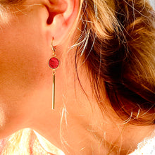 Charger l&#39;image dans la galerie, Nune longues et fines boucles d&#39;oreilles dorées Nida avec serti en cuir rubis métallisé, portée à l&#39;oreille 
