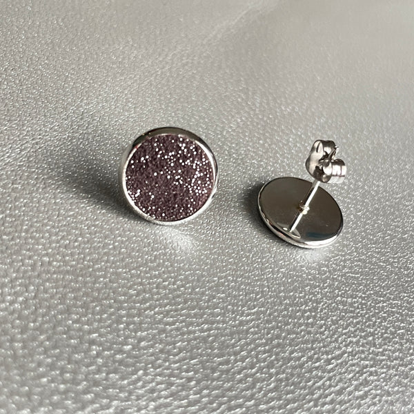 Puces d'oreilles argentées rondes Nune modèle Ilis argenté pailleté avec pastilles de cuir parme pailleté argent, sur fond de cuir gris métallisé