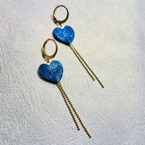 NUNE fines boucles d'oreilles dorées, petits cœurs de cuir recyclé bleu marine pailleté et chaînettes, sur fond gris
