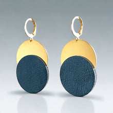 Charger l&#39;image dans la galerie, Boucles d&#39;oreilles dorées Nune modèle Eclipse avec disque de cuir bleu nuit sur un disque doré, sur fond clair
