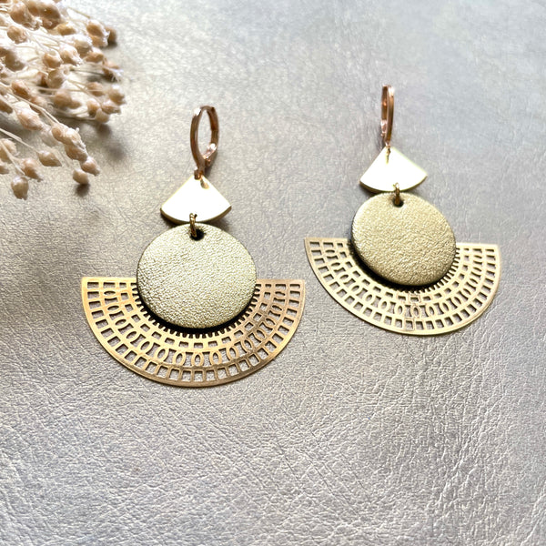 Boucles d'oreilles dorées Nune modèle Ephésia en cuir doré satiné sur fond gris doré