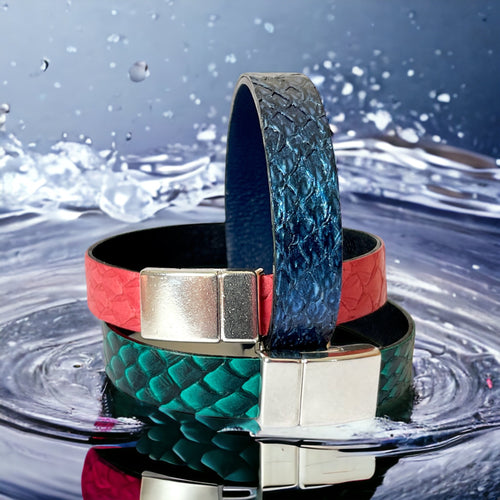 3 bracelets en cuir marin rose saumon, bleu saphir métallisé et vert émeraude écaille avec fermoirs argent aimantés, posés sur l'eau