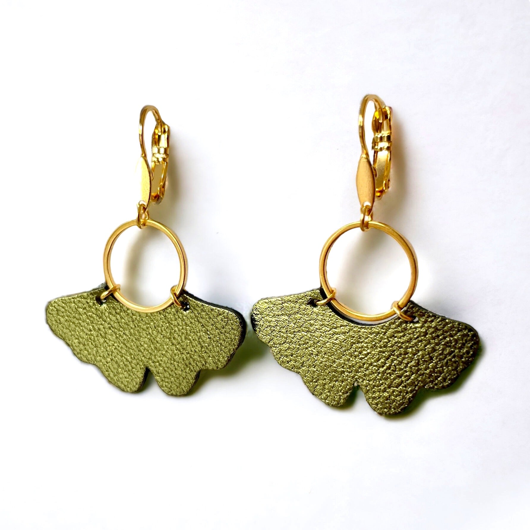 boucles d'oreilles dorées en forme de feuille de gingko en cuir kaki métallisé, sur fond blanc