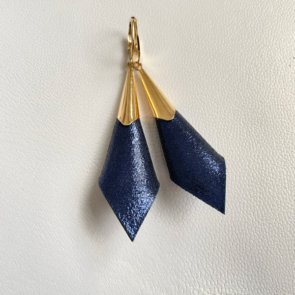 Boucles d'oreilles dorées Nune modèle Alice en forme de cônes de cuir bleu marin pailleté, sur fond cuir blanc cassé nacré