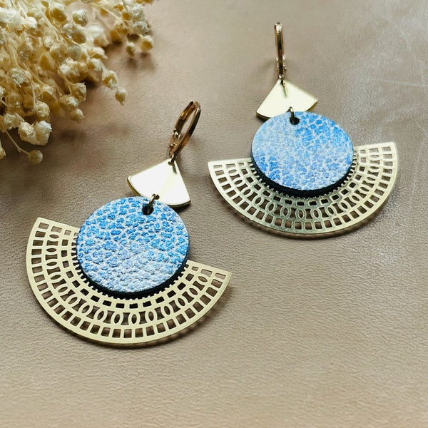 Boucles d'oreilles dorées Nune modèle Ephésia en cuir bleu ciel métal patiné sur fond gris doré