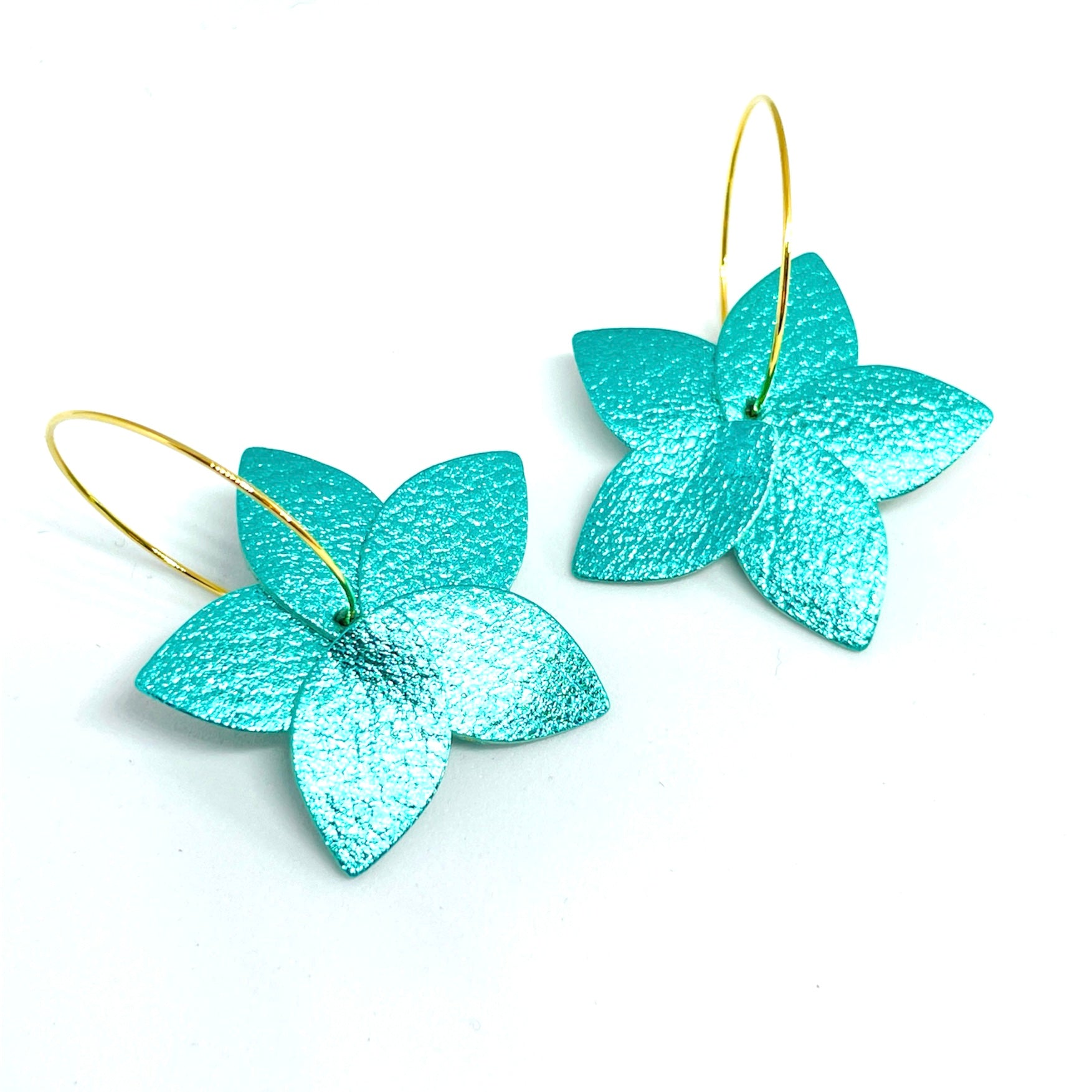 Nune petites boucles d'oreilles créoles Jasmin en cuir turquoise métallisé recyclé et anneaux en laiton doré à l'or fin, vues de dessus, sur fond blanc