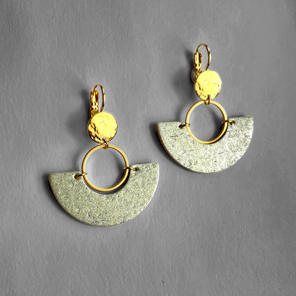 paire de boucles d'oreilles dorées en forme de demi-lunes en liège doré antique, sur fond gris