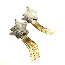 Charger l&#39;image dans la galerie, Nune Boucles d&#39;oreilles légères SuperStella, grandes étoiles en cuir argenté recyclé et leurs longues et fines chaînettes dorées, sur fond blanc
