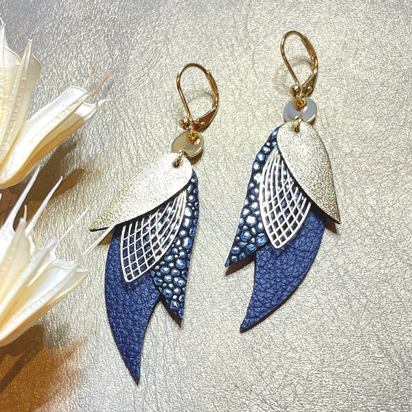 boucles d'oreilles dorées Nune modèle Ara en plumes de  cuir doré satiné, bleu nuit grainé irisé et bleu mariné grainé sur cuir beige doré