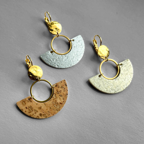 3 boucles d'oreilles dorées en forme de demi-lunes en liège brut, doré et argenté, sur fond gris