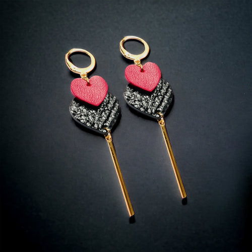 NUNE Longues boucles d'oreilles dorées modèle Félicie avec 2 cœurs imbriqués en cuirs recyclés rose fuschia et noir brillant façon lézard, sur fond noir