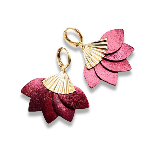 boucles d'oreilles dorées en forme éventail en cuir recyclé grenat métallisé de la marque Nune modèle Sakura, sur fond de cuir blanc