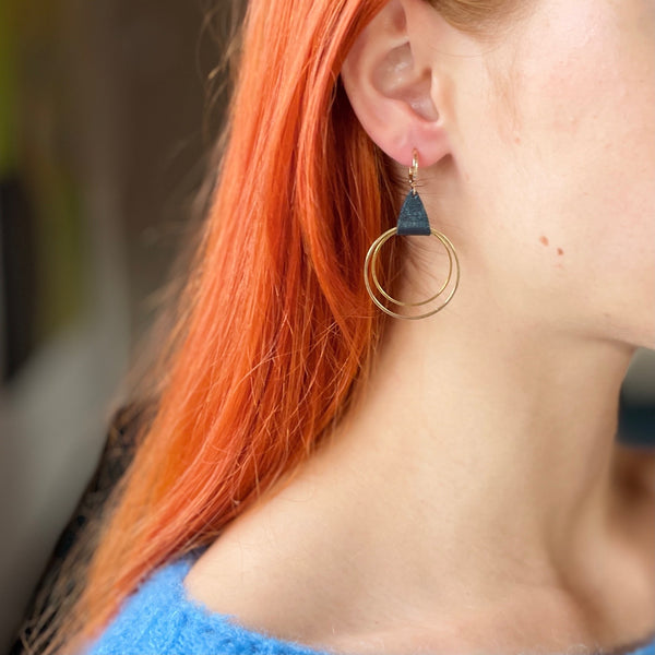 Boucle d'oreille créole dorée Nune modèle Vega en cuir bleu nuit métallisé portée par un modèle aux cheveux roux