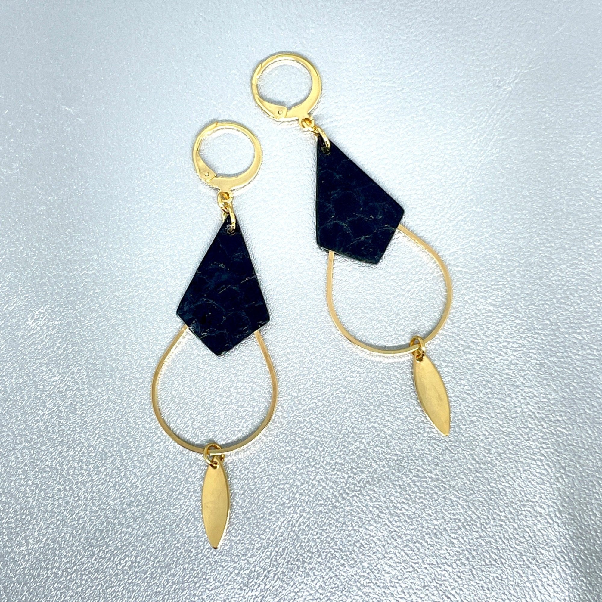 Boucles d'oreilles Gali de Nune, dorées à l'or fin avec triangle de cuir marin, cuir de poisson saumon noir d'encre, de forme grande goutte, sur fond cuir gris argenté