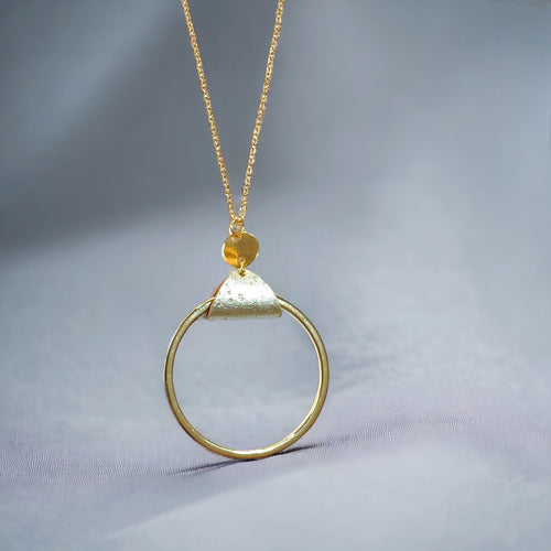 Collier fin dorée avec pendentif grand anneau créole attaché par une fine pièce de liège doré antique, sur fond gris