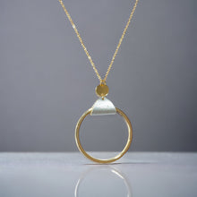 Charger l&#39;image dans la galerie, Collier fin dorée avec pendentif grand anneau créole attaché par une fine pièce de liège argenté, sur fond gris
