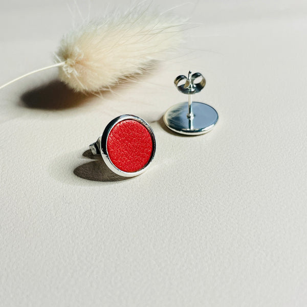 Puces d'oreilles argentées rondes Nune modèle Ilis argenté avec pastilles de cuir coquelicot nacré, sur fond de cuir blanc cassé