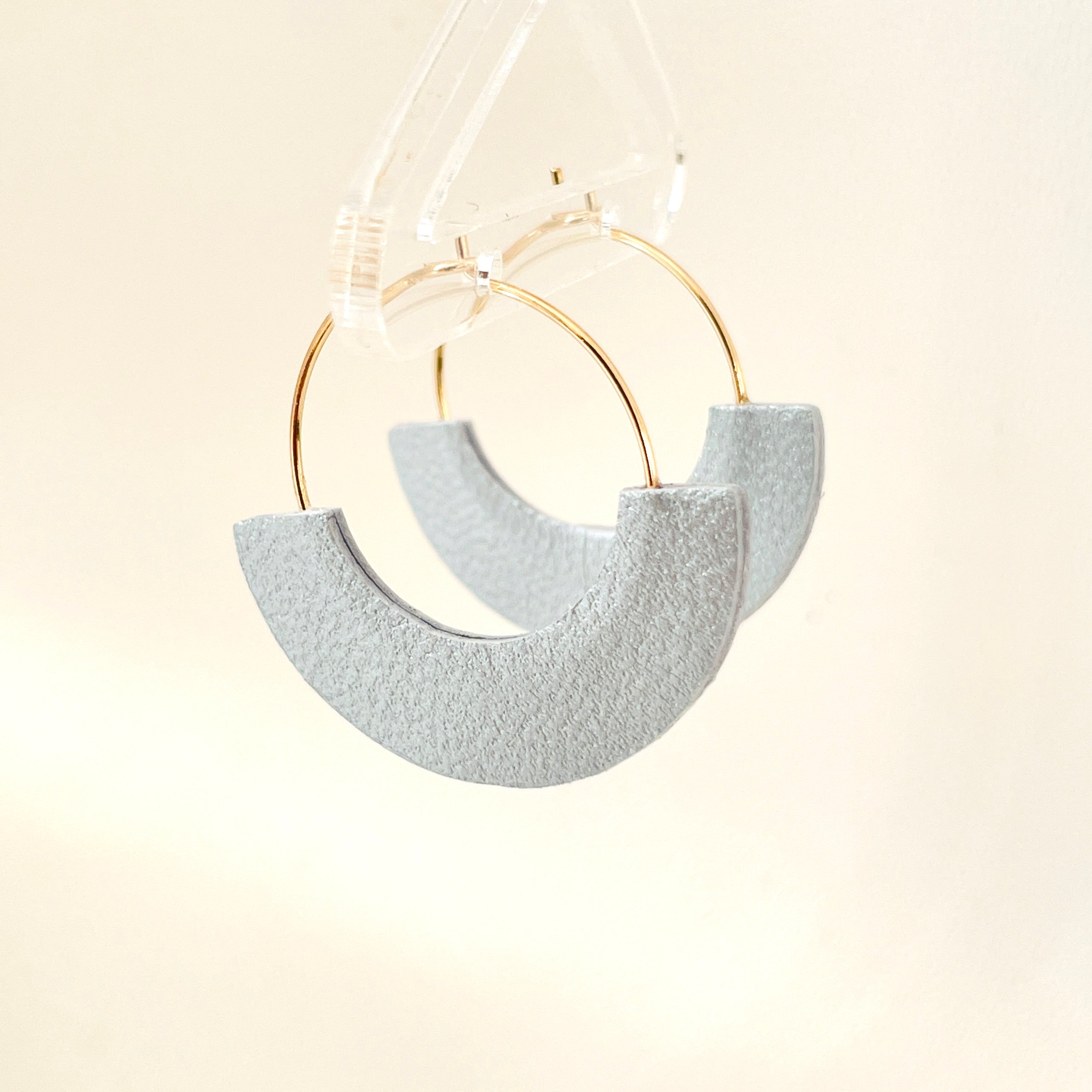 Boucles créoles Nune modèle Mezzaluna dorées en forme de demi-lunes en cuir recyclé gris métallisé