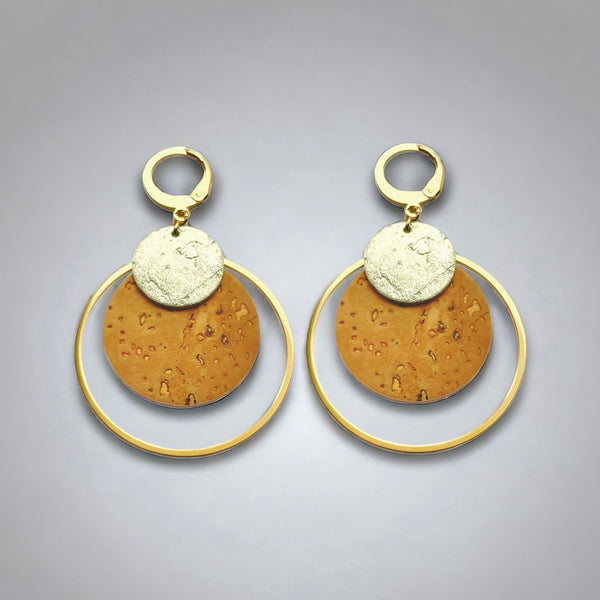 Boucles d'oreilles dorées rondes en liège brut et doré antique, soulignées par de grands anneaux dorés, sur fond gris