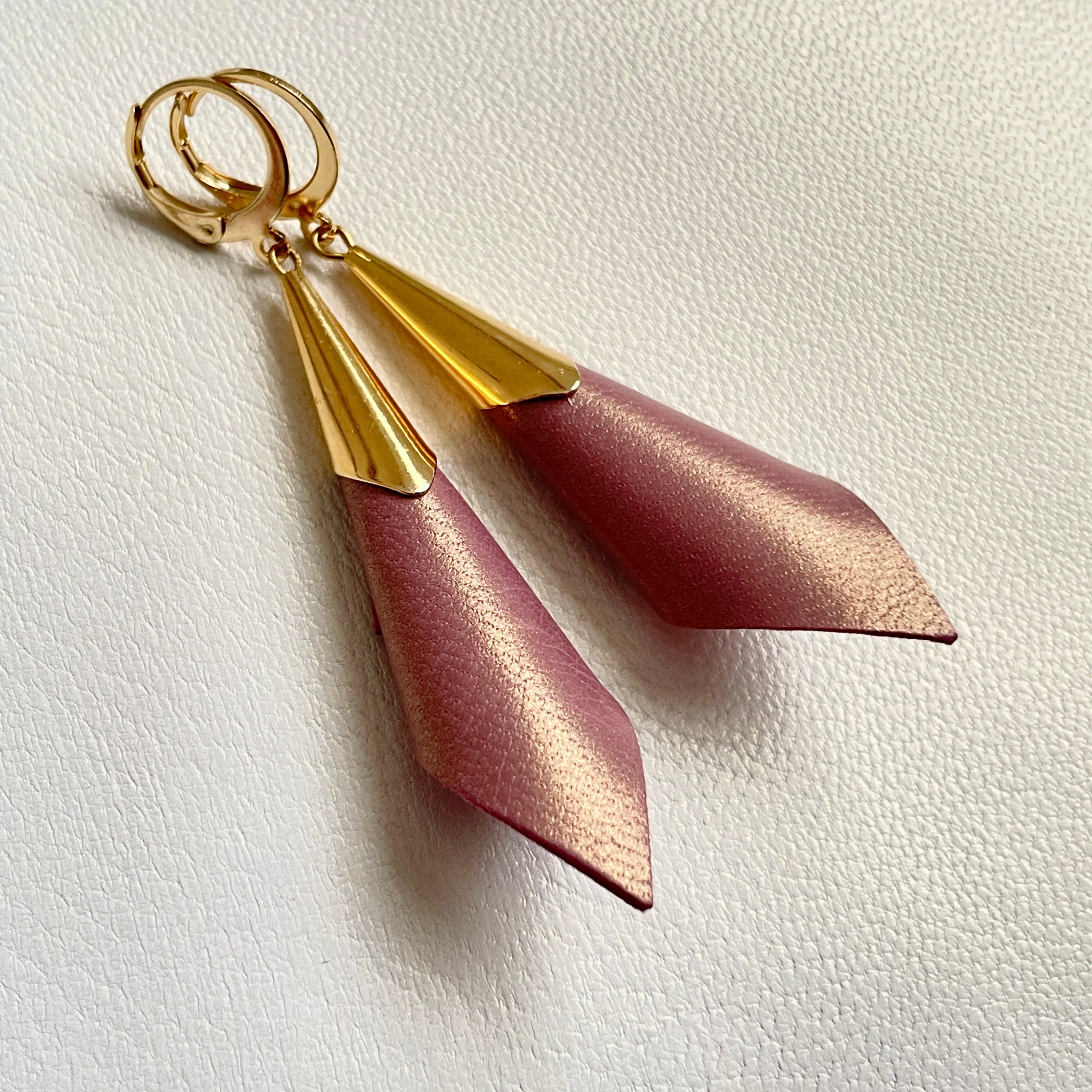 Boucles d'oreilles dorées Nune modèle Alice en forme de cônes de cuir vieux rose nacré or, sur fond cuir blanc cassé nacré